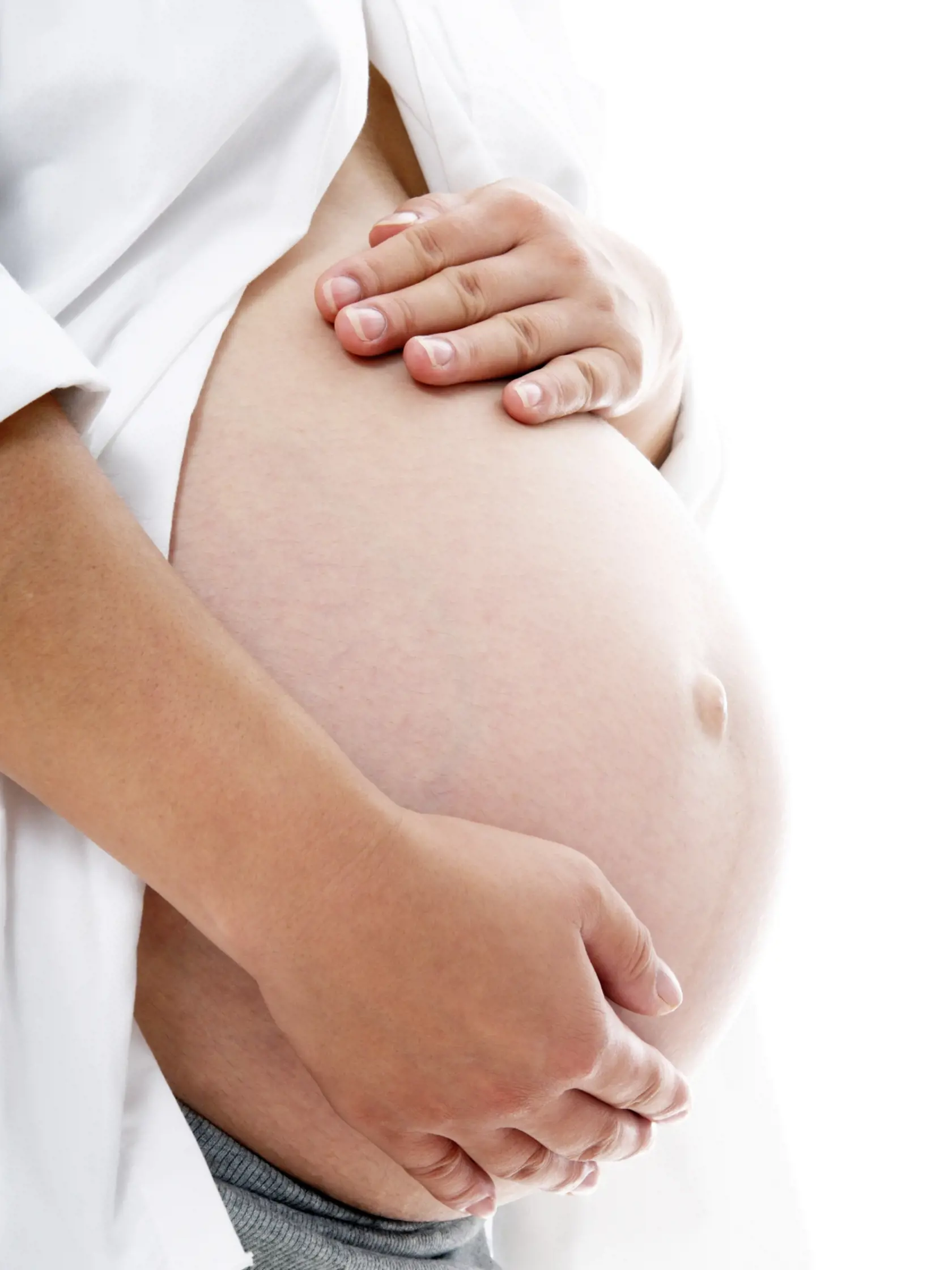 Pregnant woman holding her belly over white background.