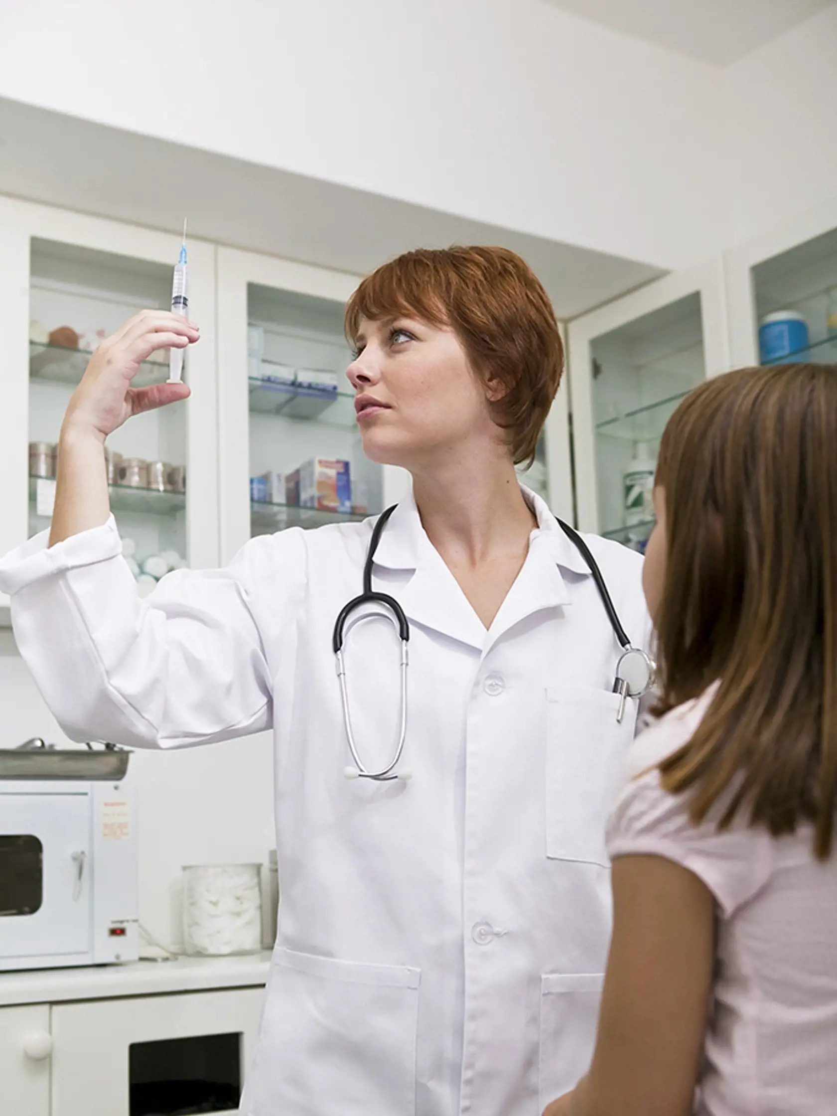 Doctor with patient and syringe in examining room
