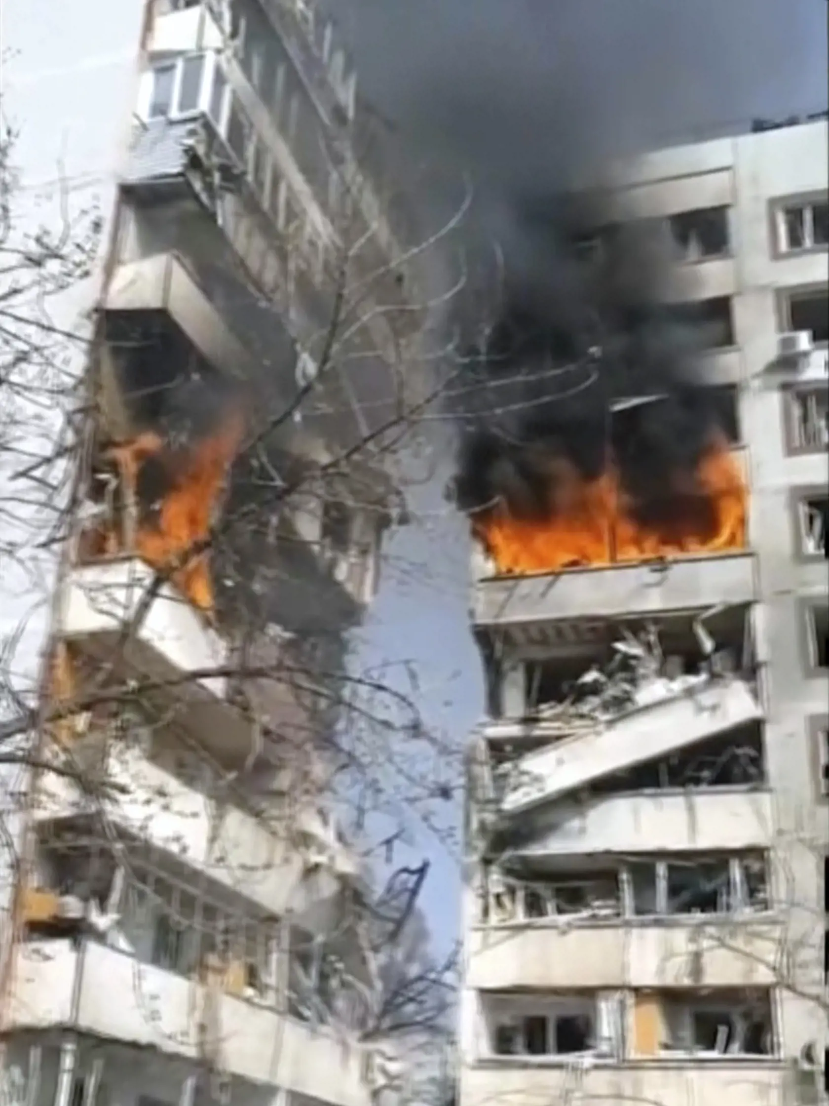 Na videosnímke, ktorú poskytla kancelária ukrajinského prezidenta, ľudia stoja pred horiacou výškovou obytnou budovou, ktorú zasiahlo ostreľovanie v meste Záporožie na juhovýchode Ukrajiny v stredu 22. marca 2023.