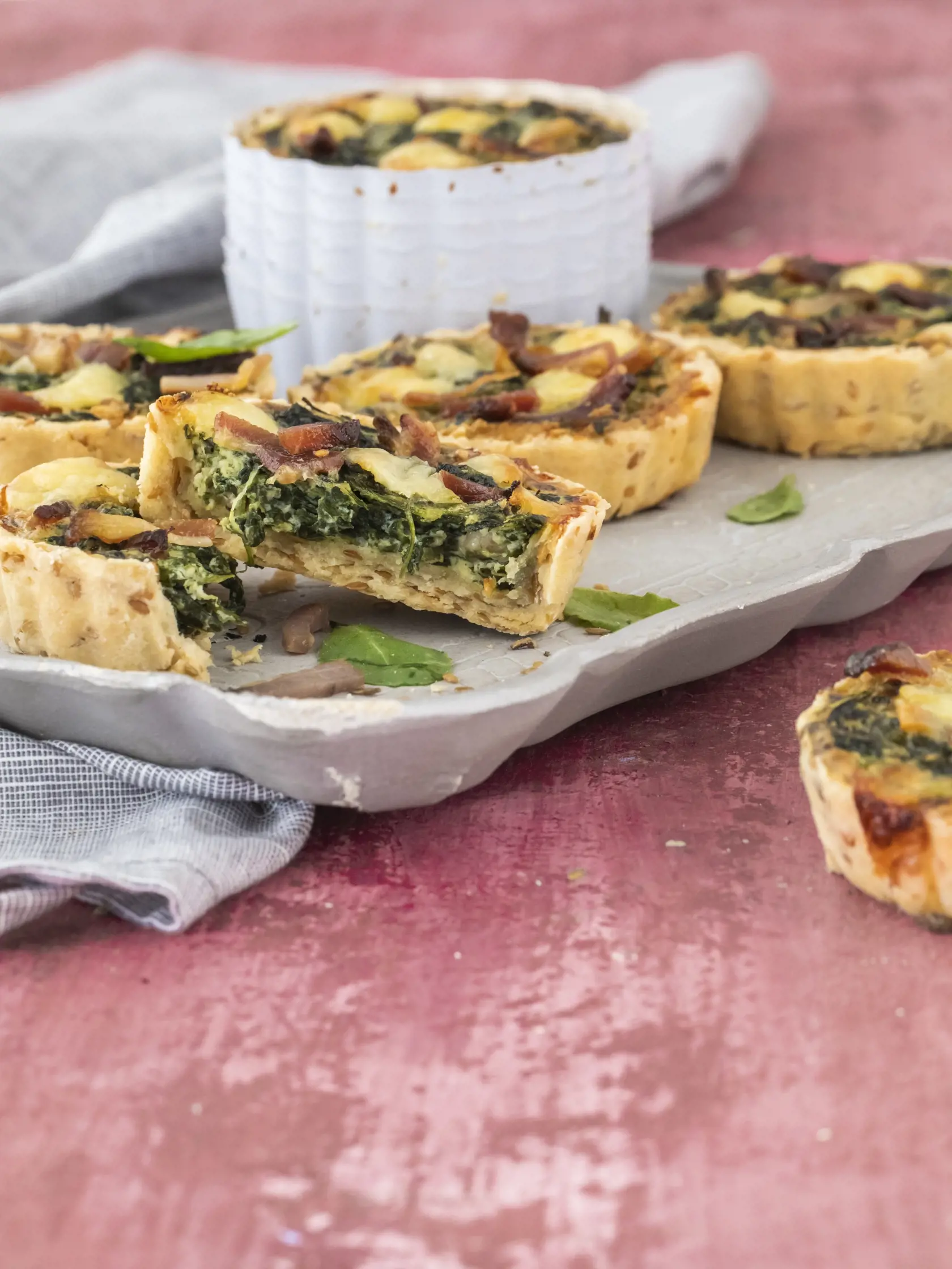špenátovo slaninové minikiše

recept:
6 KUSOV, PRÍPRAVA 30 MINÚT,
PEČENIE 35-40 MINÚT
NA CESTO:
• 175g hladkej špaldovej múky
• 30g sezamových semiačok
• 100g masla
• pol lyžičky soli
• 1 žĺtok
• 3-4 lyžice studenej vody
(ak treba)
NA NÁPLŇ:
• 1 lyžica olivového oleja
• 1 strúčik cesnaku
• 1 hrnček sparených
špenátových listov
• 3 vajcia
• 3 plátky slaniny
(nakrájanej na prúžky)
• 100g čedaru
• 200ml smotany na šľahanie
• 50g kyslej smotany
(alebo hustého jogurtu)
• štipka mletého muškátového
or