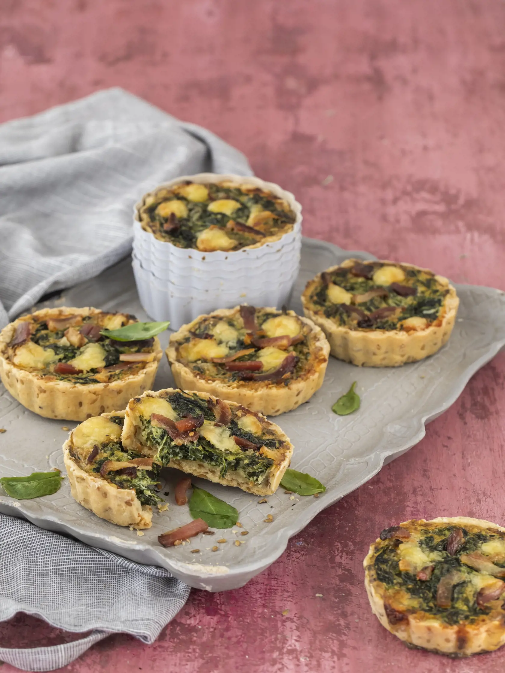 špenátovo slaninové minikiše

recept:
6 KUSOV, PRÍPRAVA 30 MINÚT,
PEČENIE 35-40 MINÚT
NA CESTO:
• 175g hladkej špaldovej múky
• 30g sezamových semiačok
• 100g masla
• pol lyžičky soli
• 1 žĺtok
• 3-4 lyžice studenej vody
(ak treba)
NA NÁPLŇ:
• 1 lyžica olivového oleja
• 1 strúčik cesnaku
• 1 hrnček sparených
špenátových listov
• 3 vajcia
• 3 plátky slaniny
(nakrájanej na prúžky)
• 100g čedaru
• 200ml smotany na šľahanie
• 50g kyslej smotany
(alebo hustého jogurtu)
• štipka mletého muškátového
or