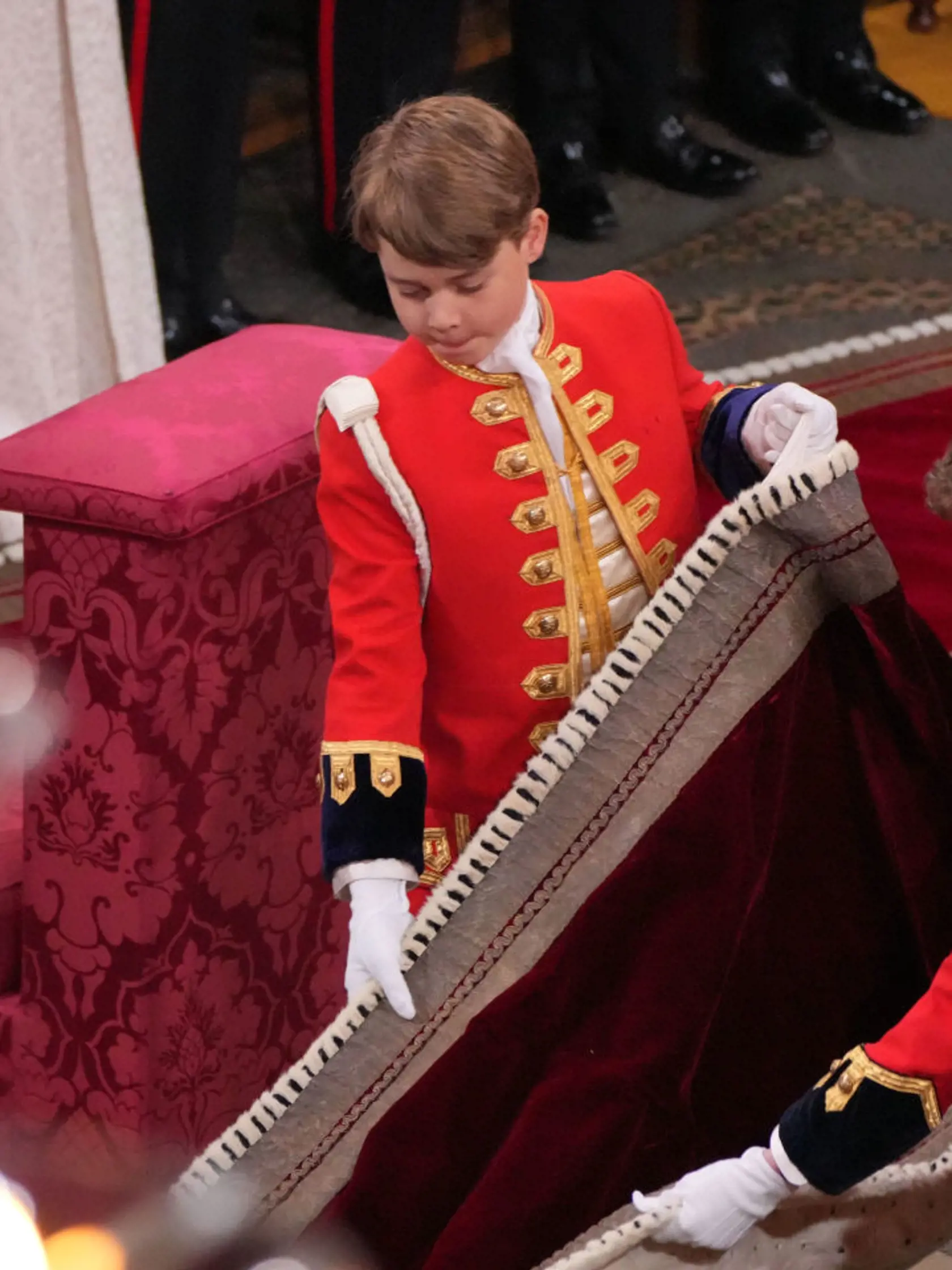 Princ George mal dôležitú úlohu - držal starému otcovi, kráľovi Karolovi III., rúcho. Ani on sa nevyhol grimasám