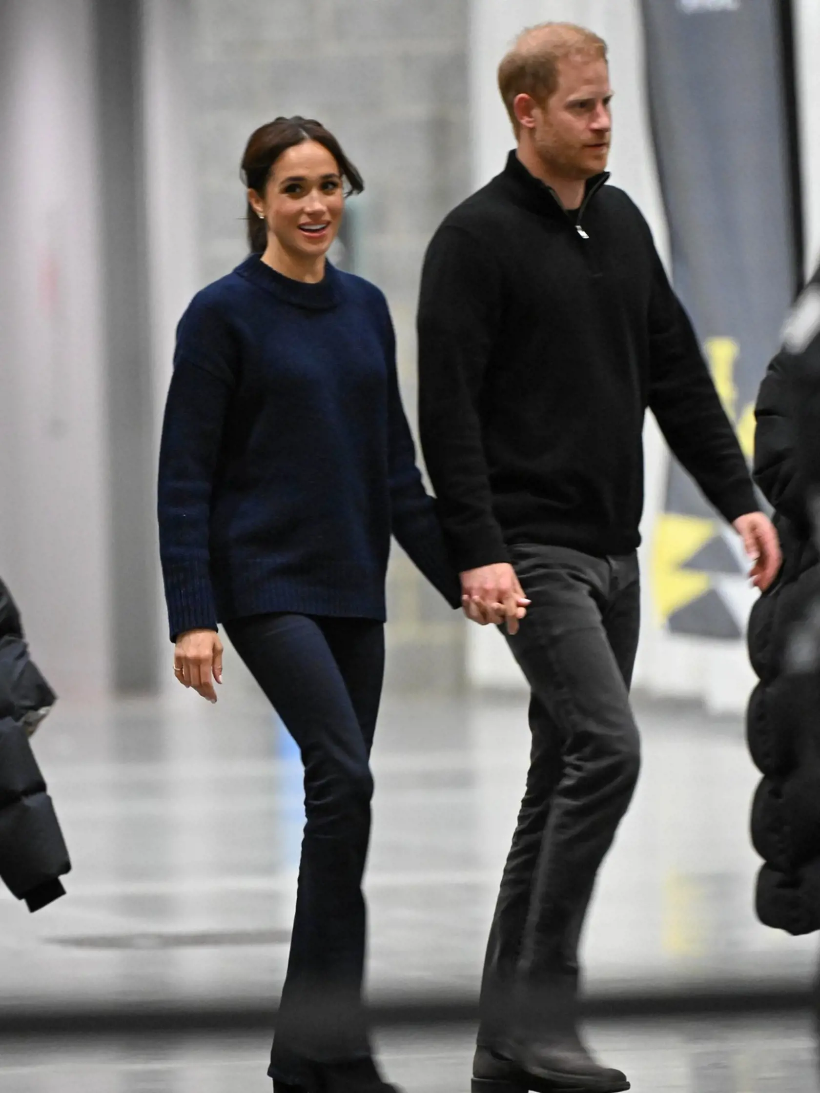 Meghan v dlhšom svetri a rozšírených nohaviciach.