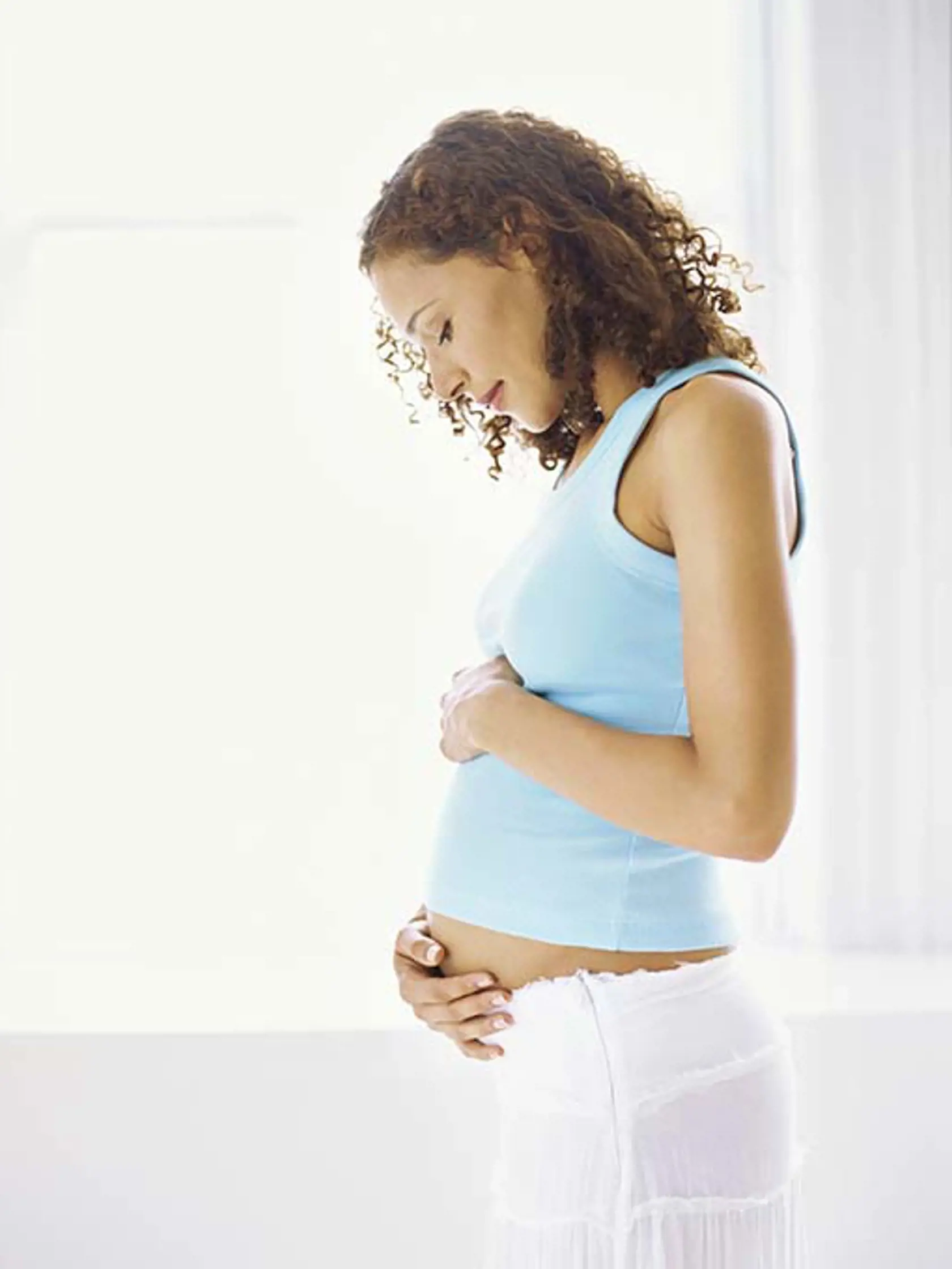 side profile of a pregnant woman touching her abdomen