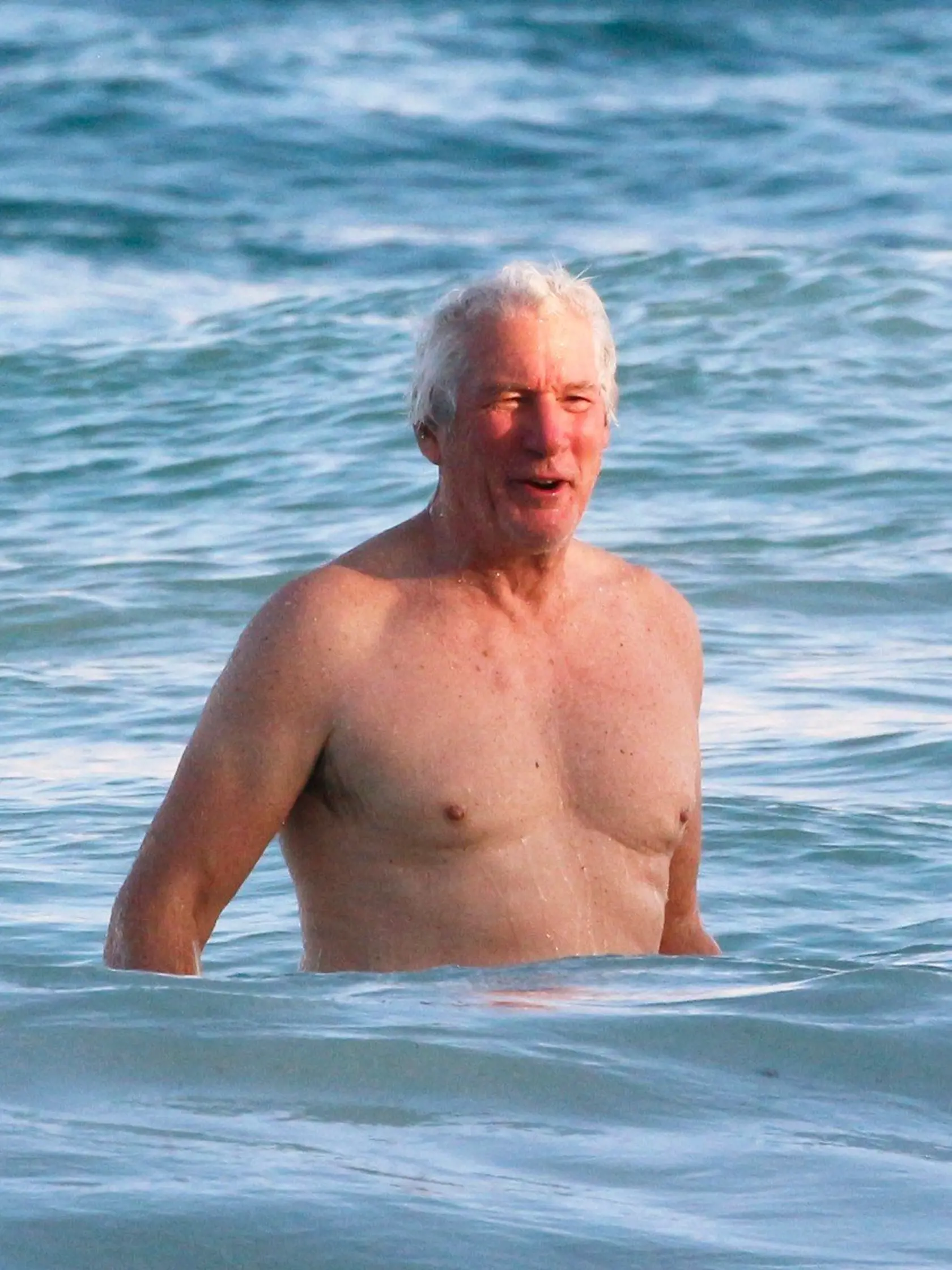 EXCLUSIVE: Richard Gere takes a dip in the ocean during his festive Mexican vacation. The 68-year-old actor got knocked over by a wave as he splashed about in the water in Tulum. Gere, who was wearing a pair of blue board shorts, looked in good shape during his sundown swim on New Year's Day. Pictured: Richard Gere, Image: 359064870, License: Rights-managed, Restrictions: -ALLCOUNTRY, Model Release: no, Credit line: Profimedia, Splash