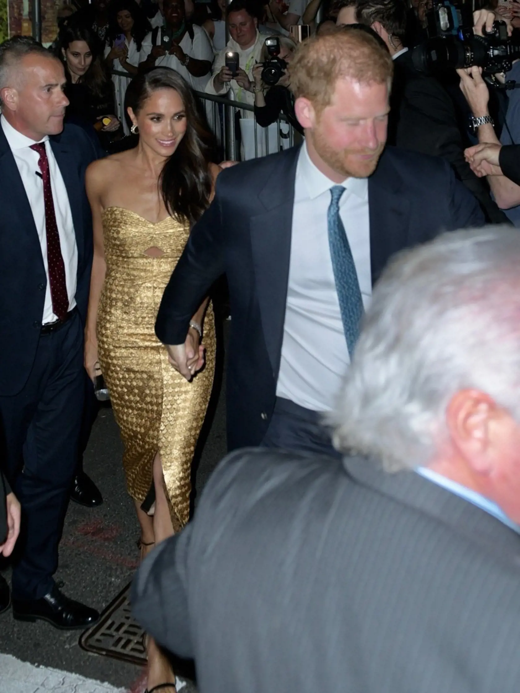 Meghan si na prestížnu udalosť obliekla zlaté obtiahnuté šaty s hlbokým výstrihom za 1 700 eur z dielne Johanny Ortiz, ktoré zladila s malou čierno-zlatou kabelkou značky Carolina Herrera za 1 100 a s topánkami na vysokých opätkoch z dielne Toma Forda za 1 350. Aby toho nebolo málo, cenu outfitu zvýšila zlatým náramkom Cartier Love v hodnote 7 350 eur.