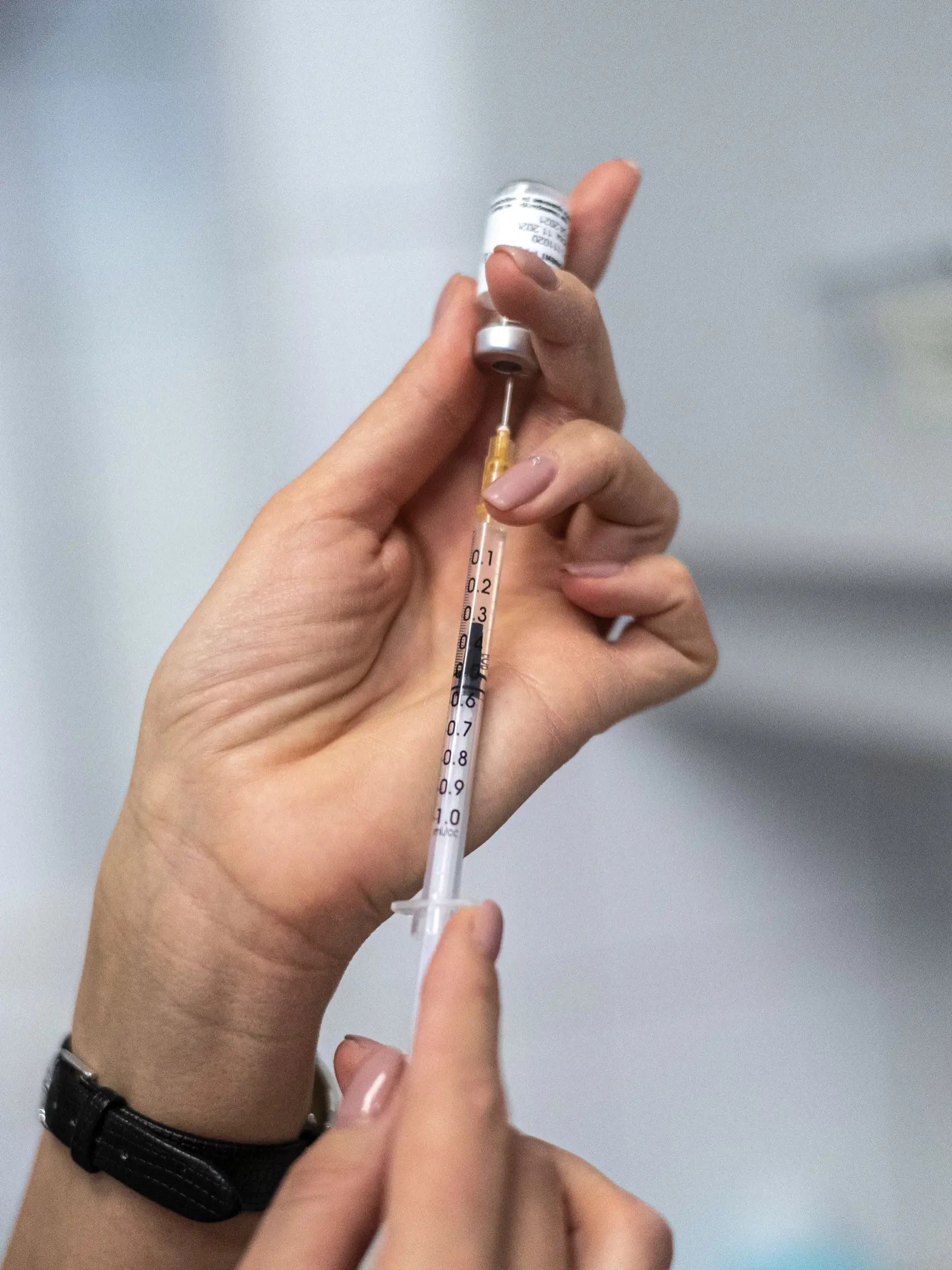 Zdravotná sestra naťahuje z ampulky do injekčnej striekačky ruskú vakcínu Sputnik V.