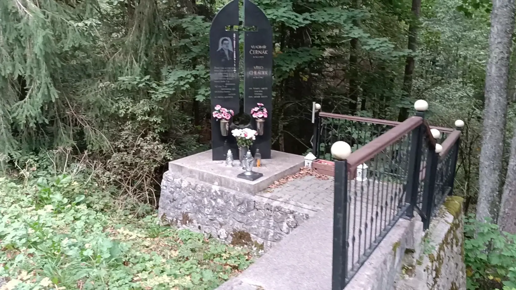 Pomník zdobí ruženec a kvety.