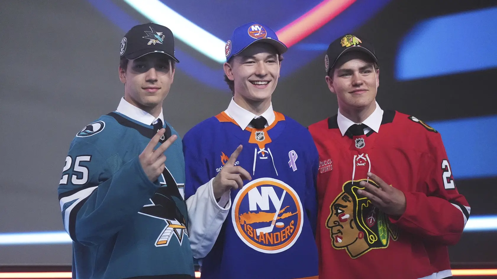 Matthew Schaefer, ktorého si ako prvého vybral tím New York Islanders, stojí uprostred medzi Michaelom Misom, ktorého ako druhého draftoval tím San Jose Sharks (vľavo), a Antonom Frondellom, ktorého si ako tretieho vybral tím Chicago Blackhawks (vpravo), počas draftu NHL.









