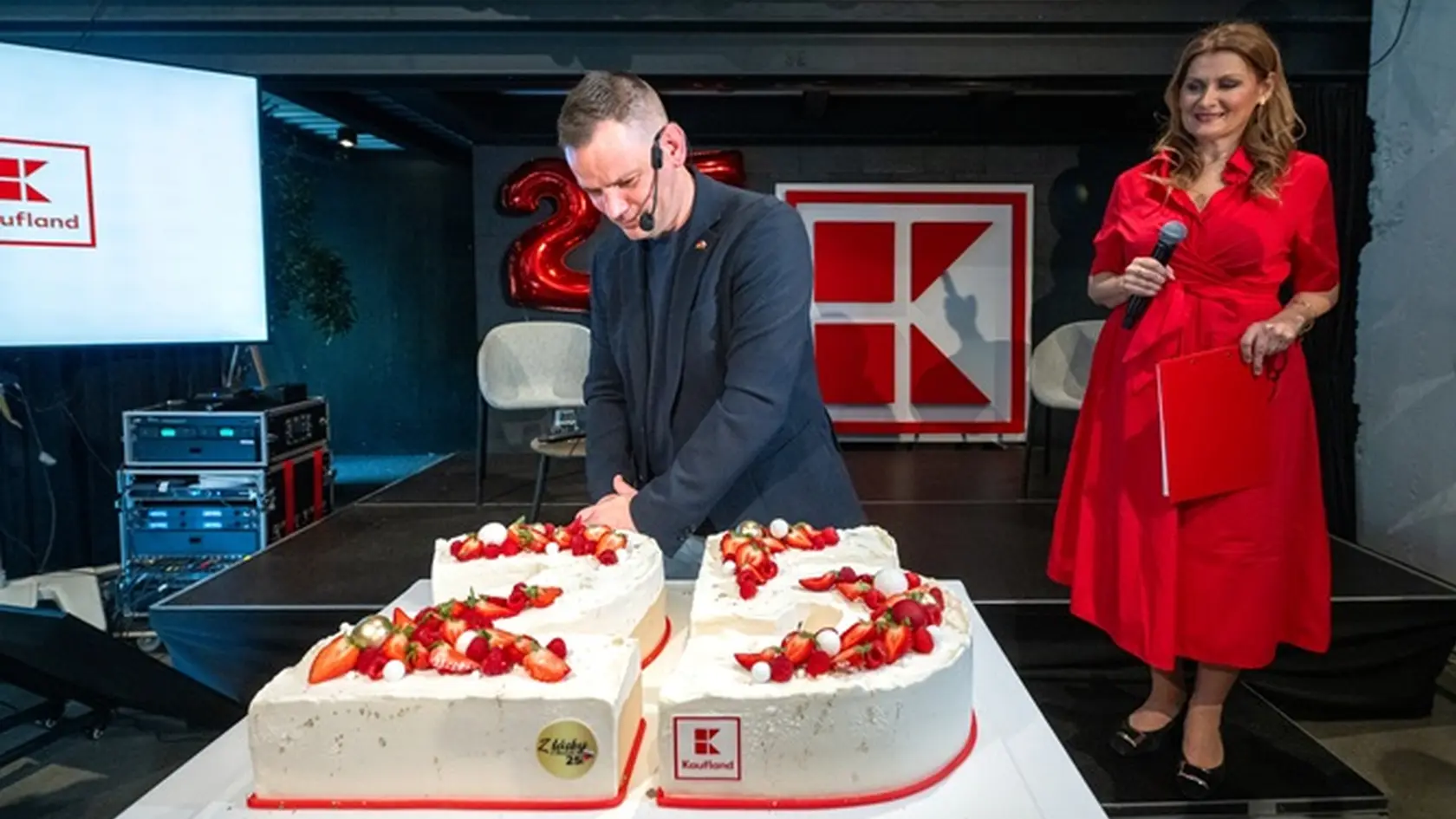 Generálny riaditeľ Kauflandu Sven Reinhard krája v Bratislave tortu. Vpravo moderátorka oslavy Katarína Brychtová.