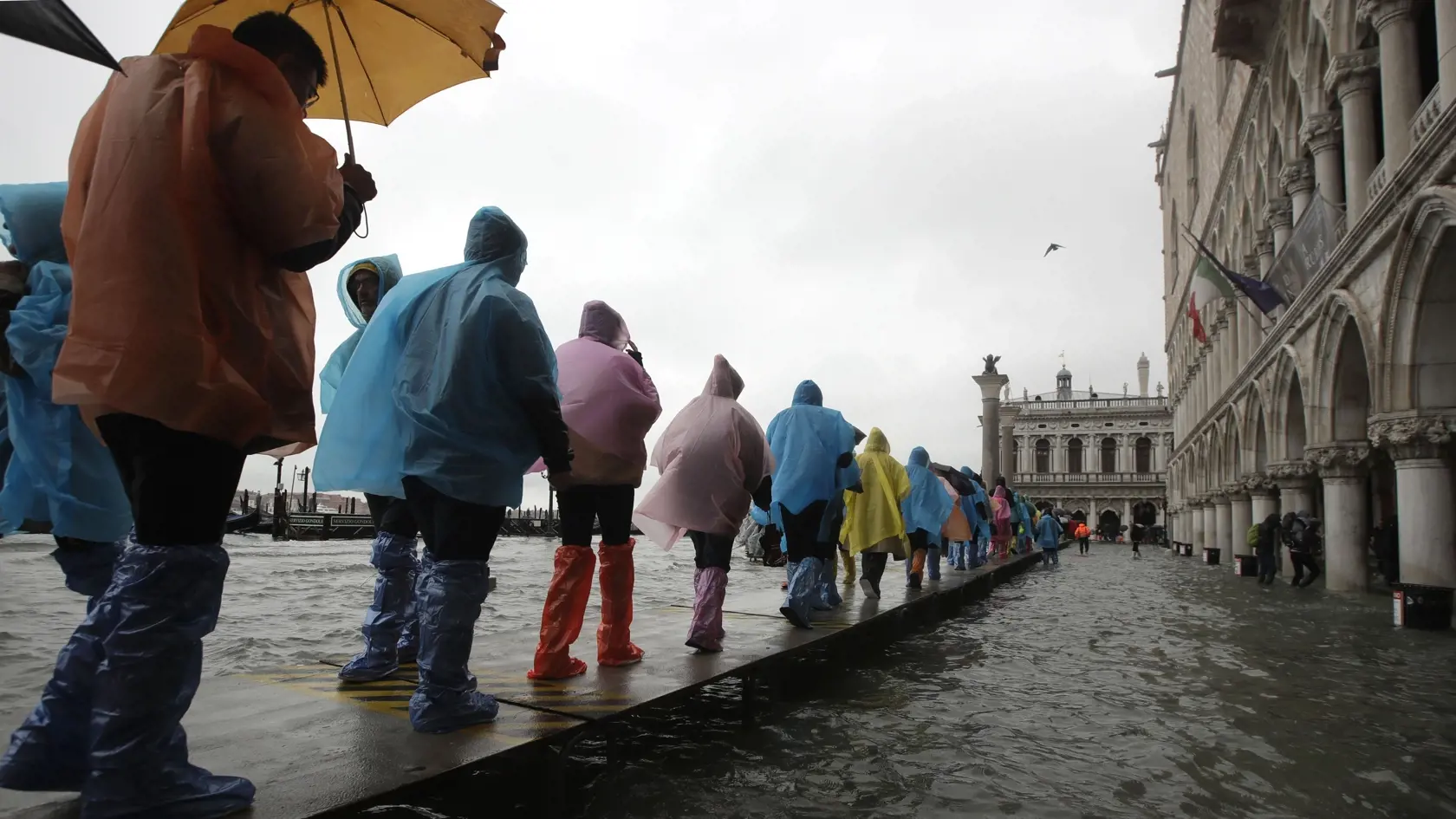 EBE 25 Benátky - Turisti kráčajú po móle v zaplavenej časti Benátok, ktoré sa v dôsledku silného prílivu ocitli sčasti pod vodou 12. novembra 2019. FOTO TASR/AP
People walk on catwalk set up on the occasion of a high tide, in a flooded Venice, Italy, Tuesday, Nov. 12, 2019. The high tide reached a peak of 127cm (4.1ft) at 10:35am while an even higher level of 140cm(4.6ft) was predicted for later Tuesday evening. (AP Photo/Luca Bruno)
