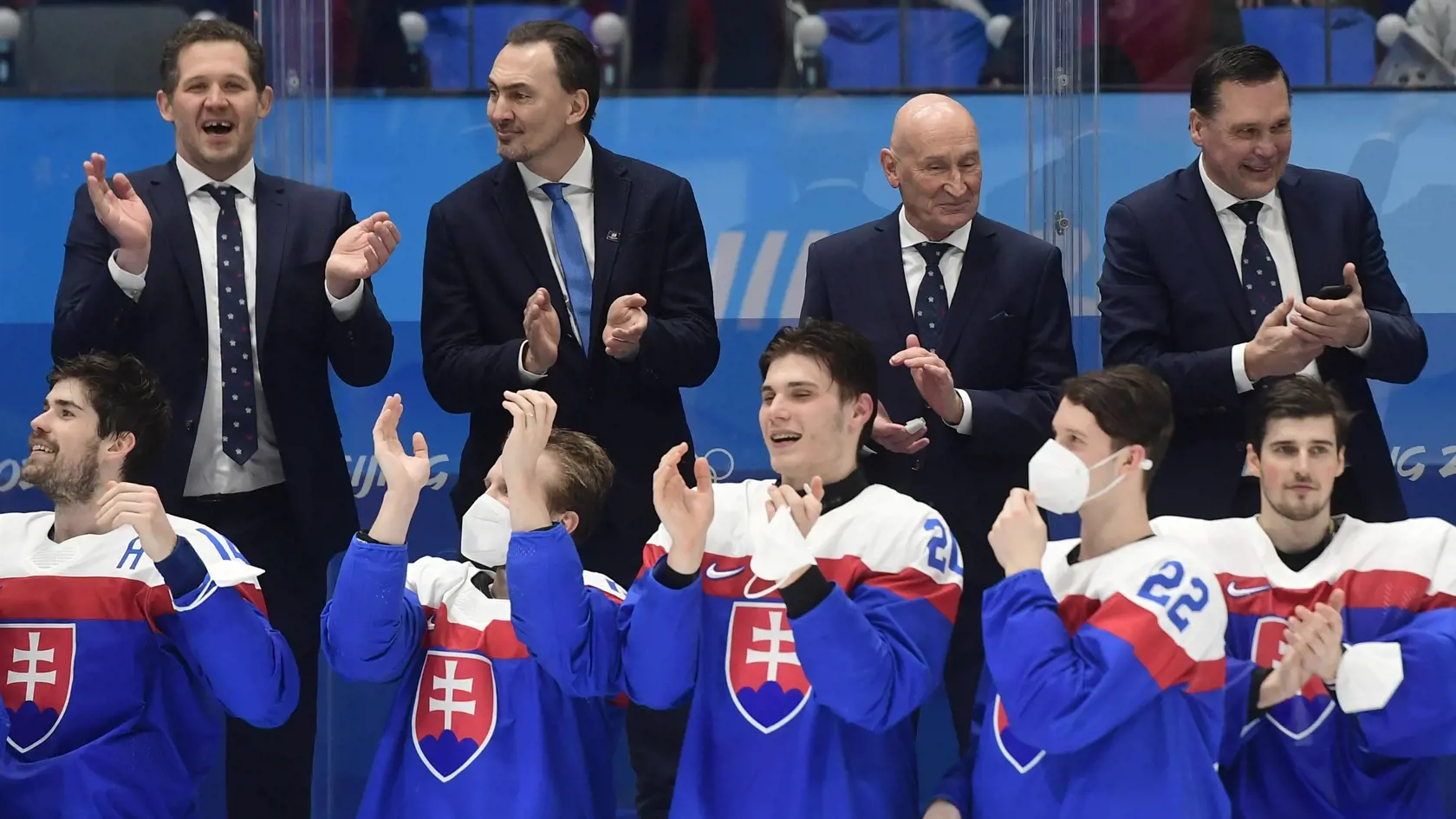 Na snímke v pozadí slovenská striedačka zľava tréner brankárov Ján Lašák, prezident SZĽH a generálny manažér slovenských hokejistov Miroslav Šatan, tréner slovenských hokejistov Slovenska Craig Ramsay a asistent generálneho manažéra Oto Haščák, na snímke dole zľava Peter Čerešňák, Michal Krištof, Juraj Slafkovský, Samuel Kňažko a brankár Patrik Rybár oslavujú po zisku bronzu po zápase olympijského turnaja v hokeji mužov o bronz Slovensko - Švédsko na ZOH 2022 v Pekingu v sobotu 19. februára 2022