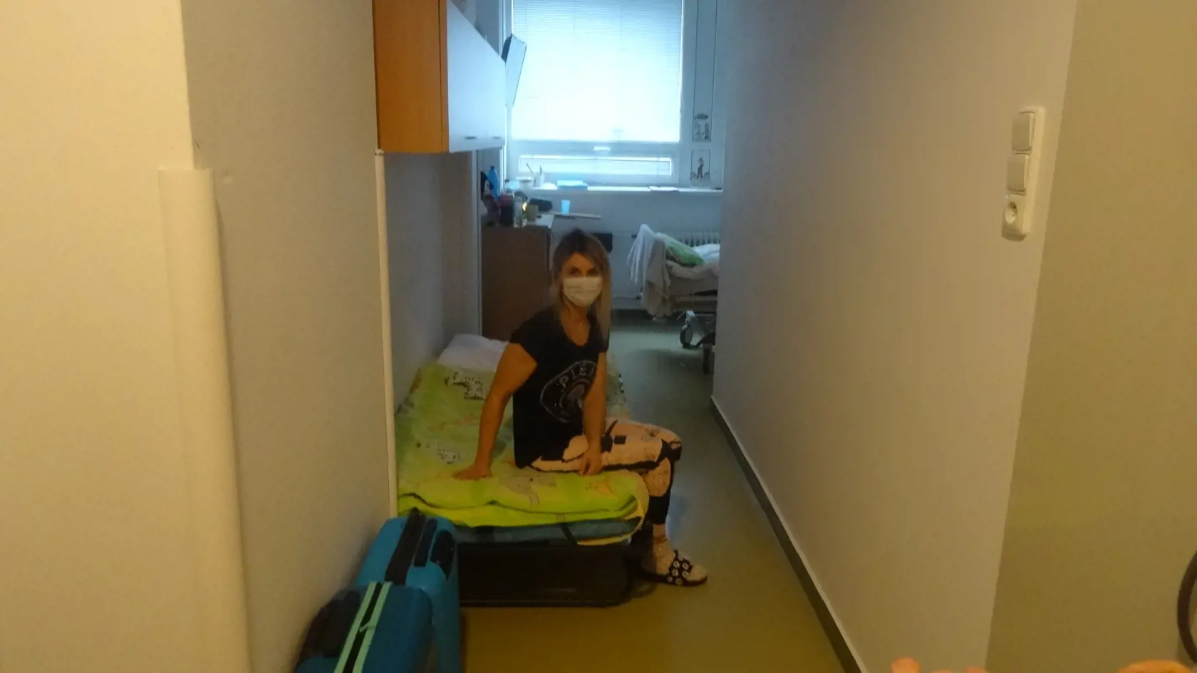 Mama ťažko chorého chlapčeka spí na skladacom lôžku pri dverách kúpeľne.