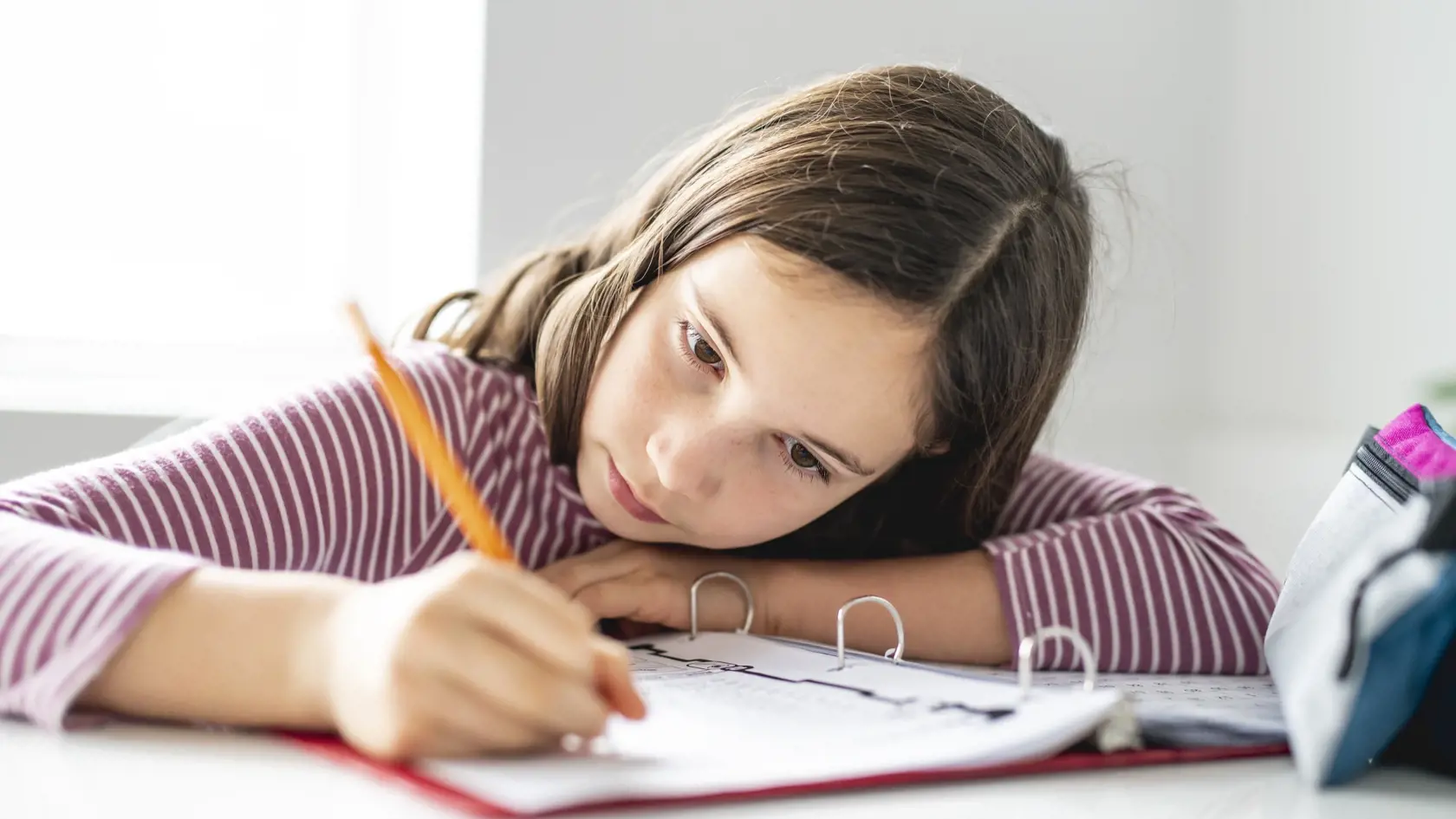 schoolgirl doing homework on the diner table