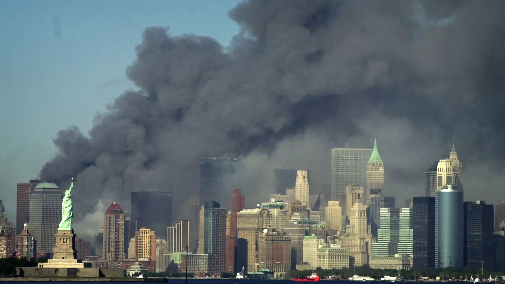 Na archívnej snímke z 11. septembra 2001 dym stúpa pred Sochou slobody z miesta pádu Svetového obchodného centra v New Yorku (WTC).