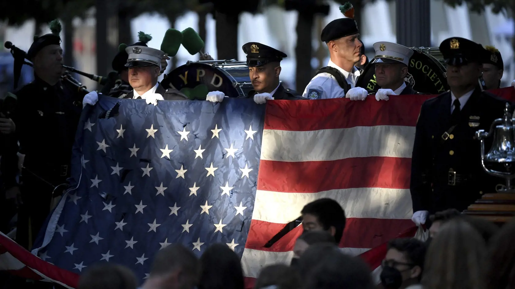 Na snímke newyorksí policajti a hasiči nesú americkú vlajku počas spomienkového ceremoniálu na mieste Národného pamätníka a múzea 11. septembra 2001 pri príležitosti dvadsiateho výročia teroristických útokov na USA, 11. septembra 2021 vo Washingtone.
