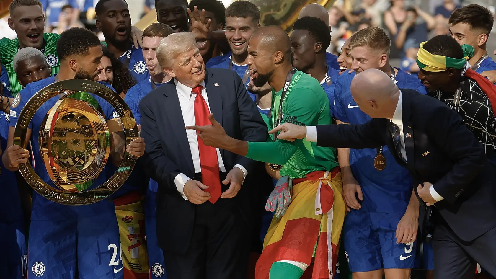 Prezident FIFA Gianni Infantino odháňa prezidenta USA Donalda Trumpa z pódia v momente, keď chcú hráči Chelsea Londýn zdvihnúť trofej pre majstrov sveta klubov FIFA.
