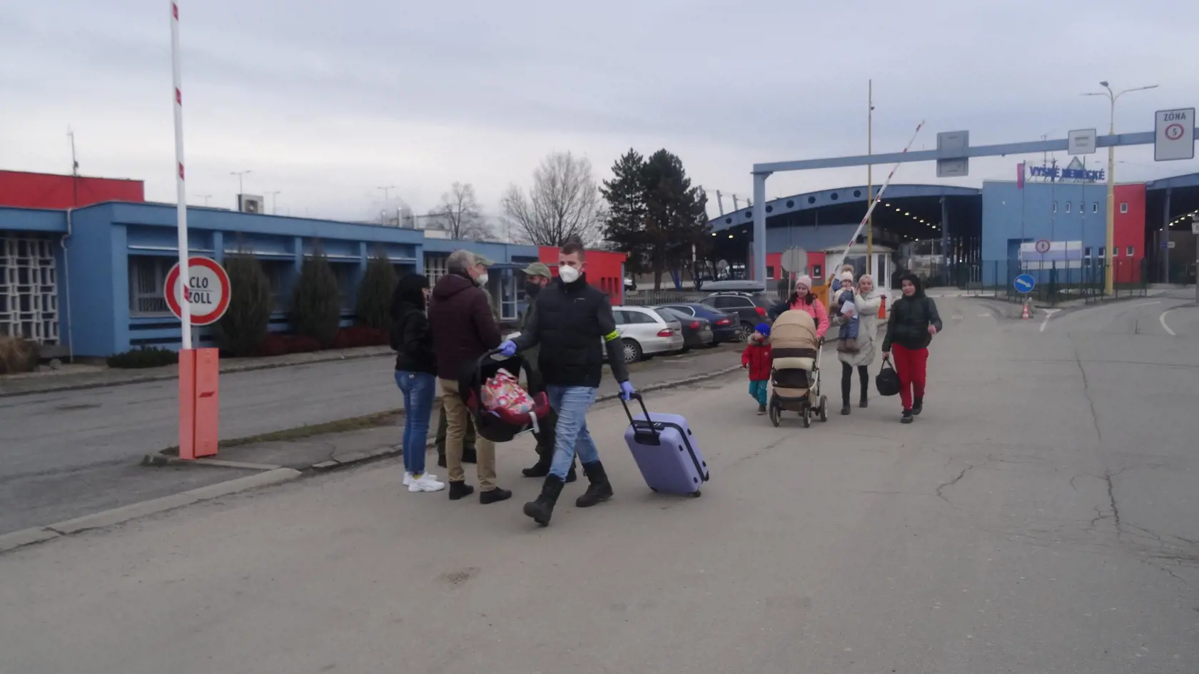 Utečenci prichádzali v menších skupinách. Policajt nesie žene kufor  a detskú sedačku.