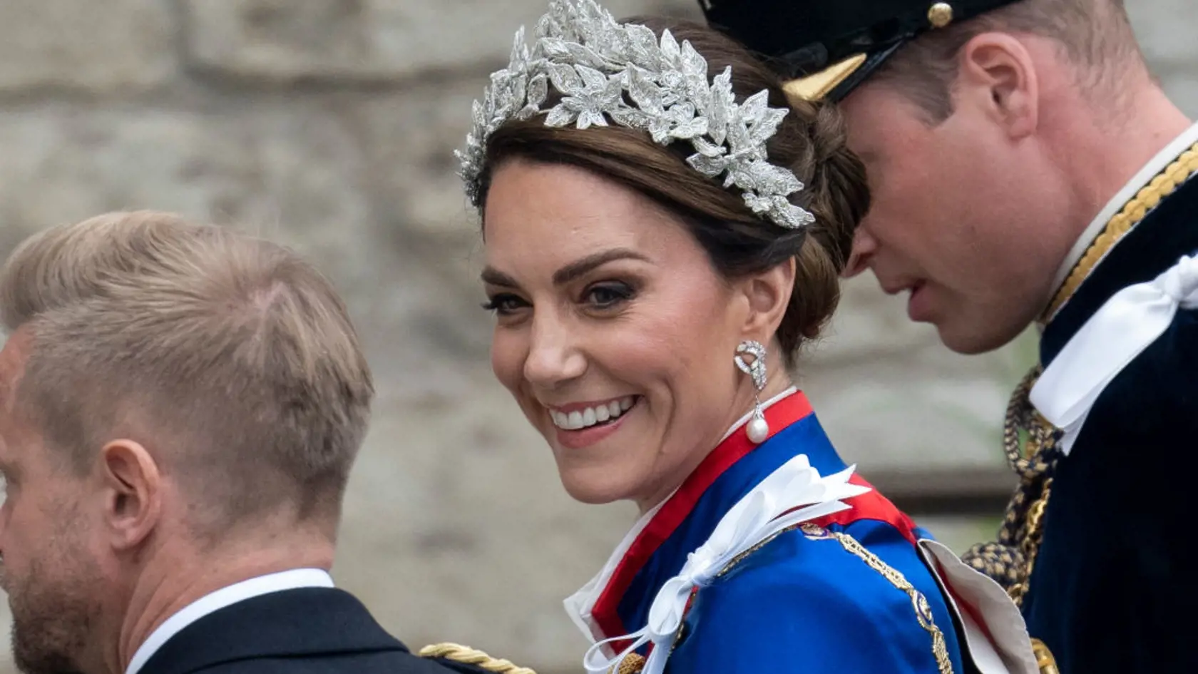 Princezná Kate mala na sebe tradičný ceremoniálny plášť. Pod ním slonovinové šaty od Alexandra McQueena a 3D čelenku, rovnako tak aj jej dcéra, princezná Charlotte.