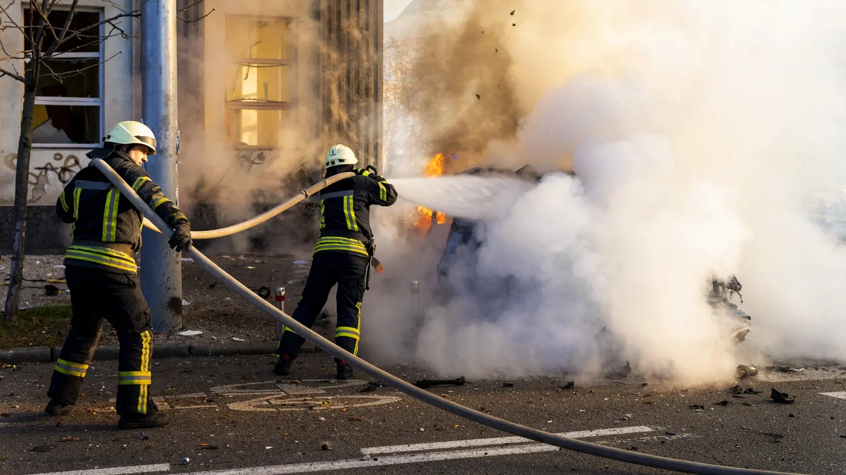 Hasiči sa pokúšajú uhasiť horiace auto po ruskom raketovom útoku v Kyjeve 10. októbra 2022.