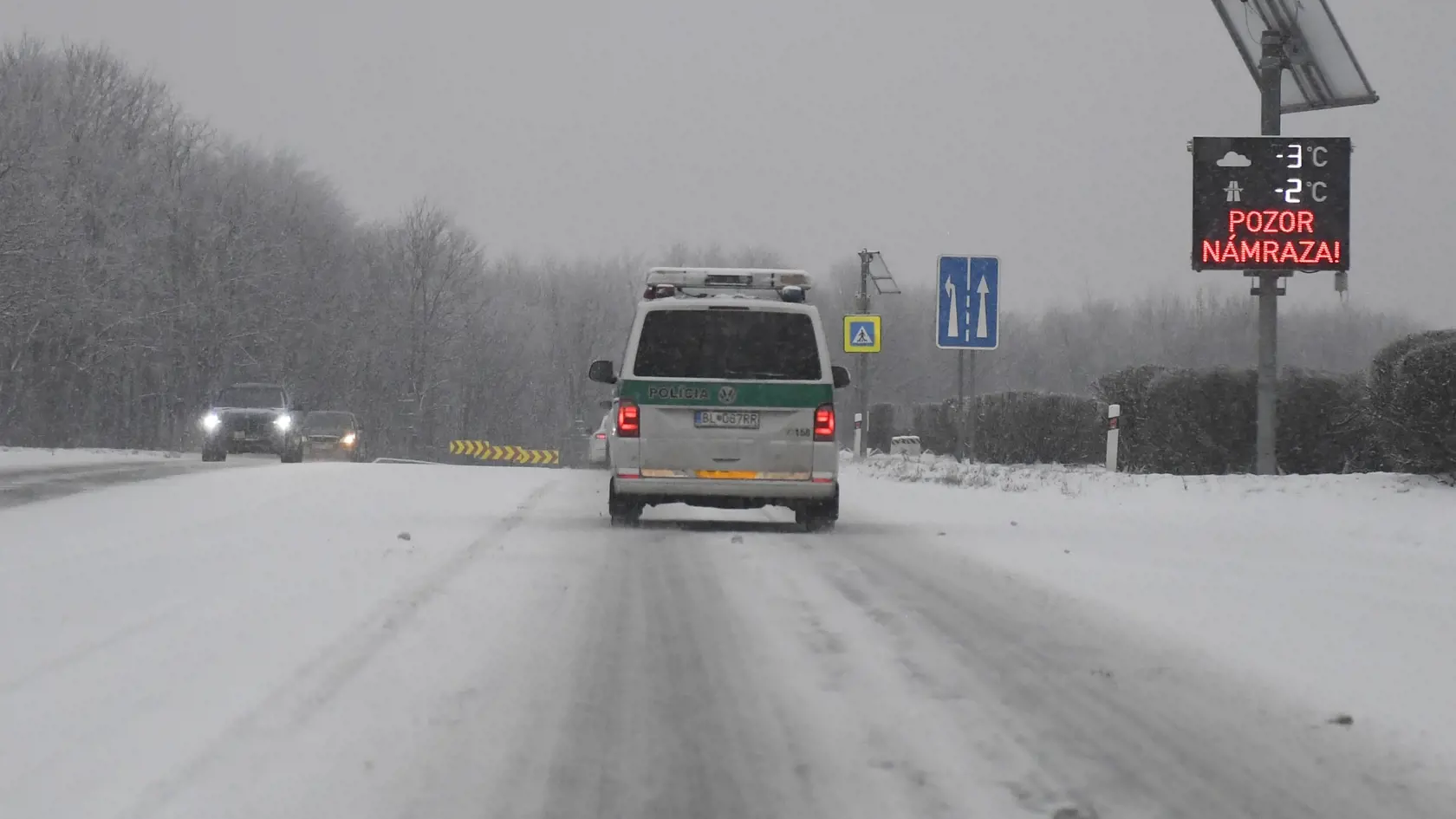 Na snímke policajné auto prechádza počas sneženia okolo tabule s nápisom Pozor námraza cez horský priechod Dargov v utorok 23. januára 2024. FOTO TASR - František Iván