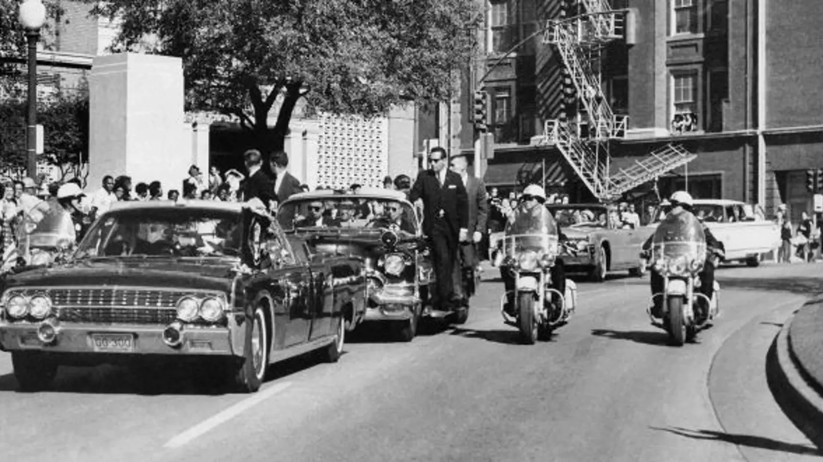 KK16 Dallas - Na archívnej snímke z 22. novembra 1963 americký prezident John f. Kennedy zdvíha ruku pred hlavu pár sekúnd pred streľbou, prvá dáma USA Jacqueline Kennedyová drží jeho predlaktie, počas jazdy otvoreným lincolnom na Elm Street v Dallase. Dňa 22. novembra 2013 uplynie od atentátu na prezidenta Johna Fitzgeralda Kennedyho 50 rokov. Stalo sa to 22. novembra 1963 počas jeho cesty po Texase, ktorú absolvoval v súvislosti s blížiacimi sa prezidentskými voľbami. FOTO TASR/AP 
FILE - In t