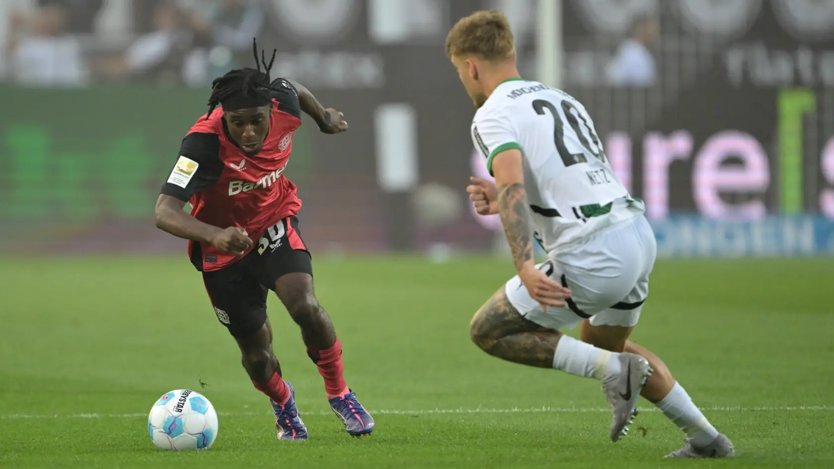 Hráč Leverkusenu Jeremie Frimpong (vľavo) bojuje o loptu s Lucom Netzom z Mönchengladbachu v zápase nemeckej Bundseligy.