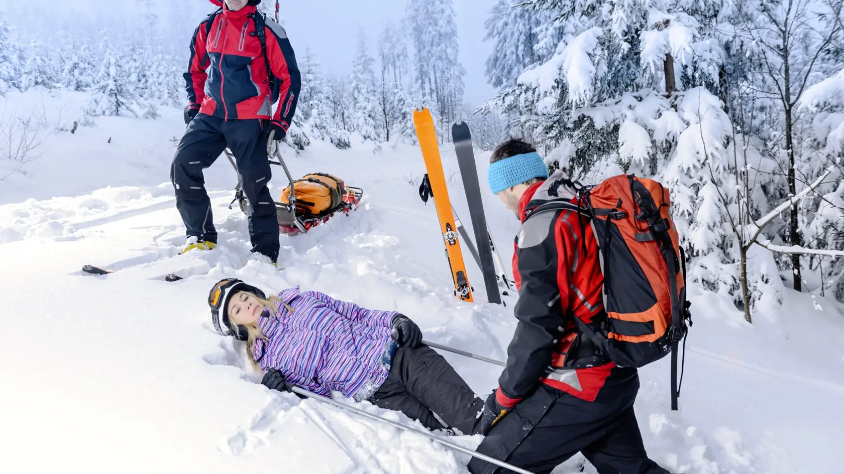 Rescue ski patrol help injured woman skier lying in snow