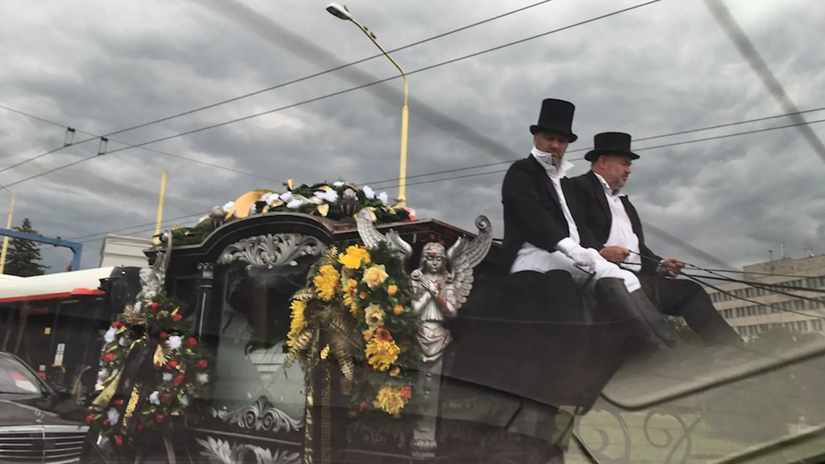 Jazdu pohrebného koča sledovali vodiči áut na rušnej križovatke.