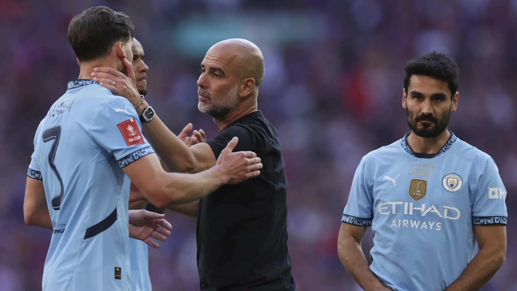 Tréner Manchestru City Pep Guardiola (uprostred) a futbalista Manchestru City Ruben Dias sa objímajú.