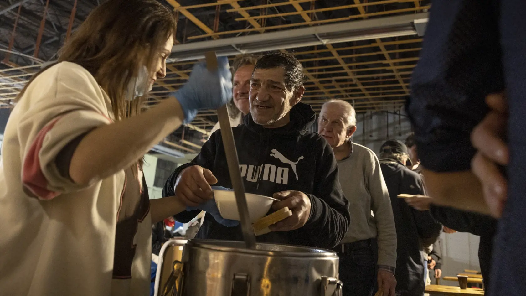 Klienti nocľahárne si po dlhom a mrazivom dni vychutnávajú teplú večeru.