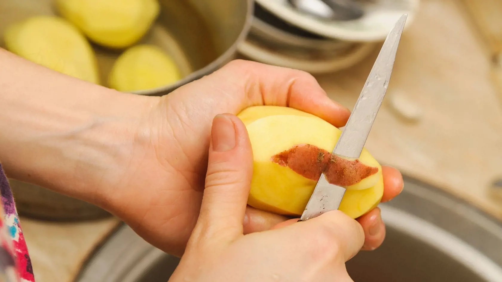 Woman cutting to peel potatoes. Kitchen working. Prepare food
