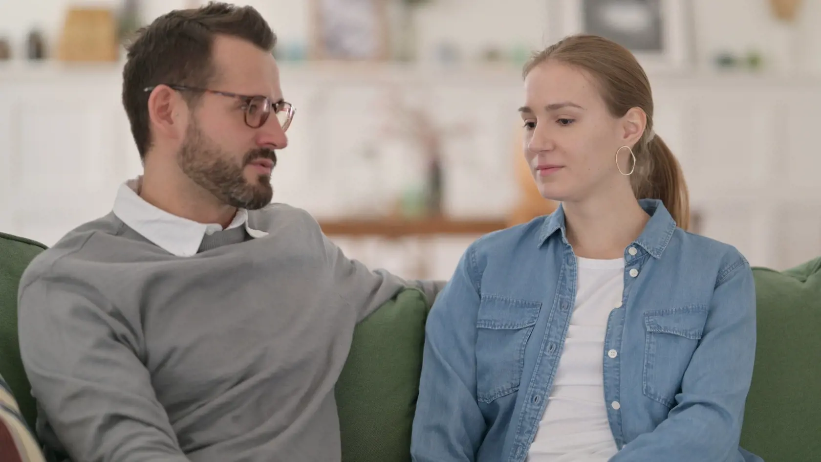 Happy,Couple,Having,Conversation,While,Sitting,On,Sofa
