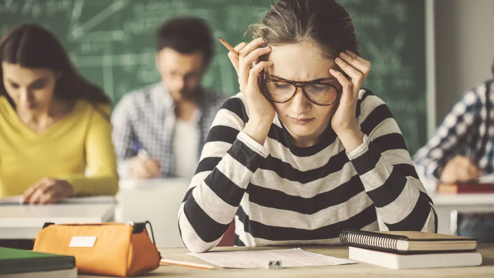 Students solving problem quiz in classroom behind blackboard