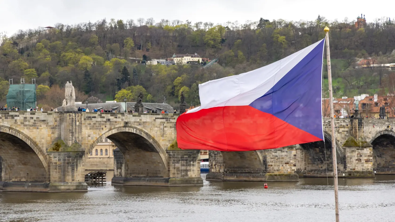 Česká vlajka s Karlovým mostom v pozadí.