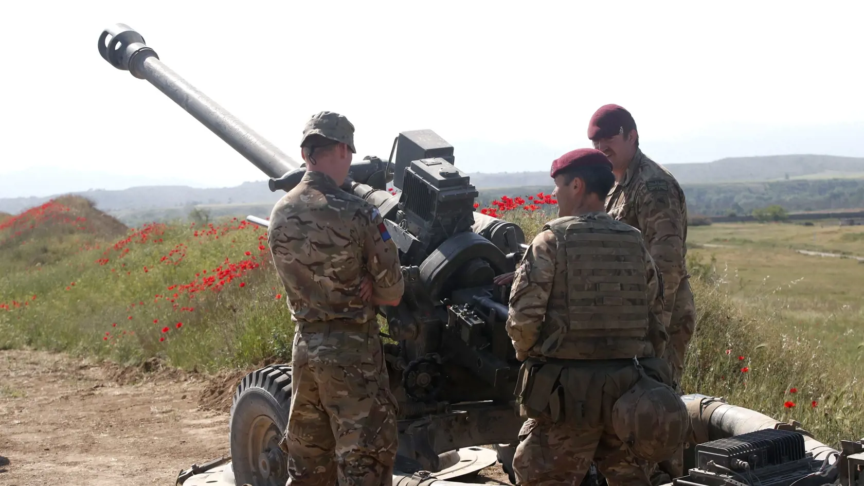 PK 10 Krivolak - Britskí vojaci zo 16. leteckej brigády stoja pri húfnici počas vojenských cvičení NATO Swift Response 22 (Rýchla odozva) ponad armádnym výcvikovým areálom Krivolak v centrálnej časti Severného Macedónska vo štvrtok 12. mája 2022. Cvičenia sú zamerané na preukázanie pripravenosti nasadenia pozdĺž východnej hranice NATO a zahŕňajú napríklad zoskoky s padákom na rôznych miestach krajiny. Na manévroch sa zúčastňuje zhruba 10.000 vojakov z 19 krajín. FOTO TASR/AP

British soldiers fr