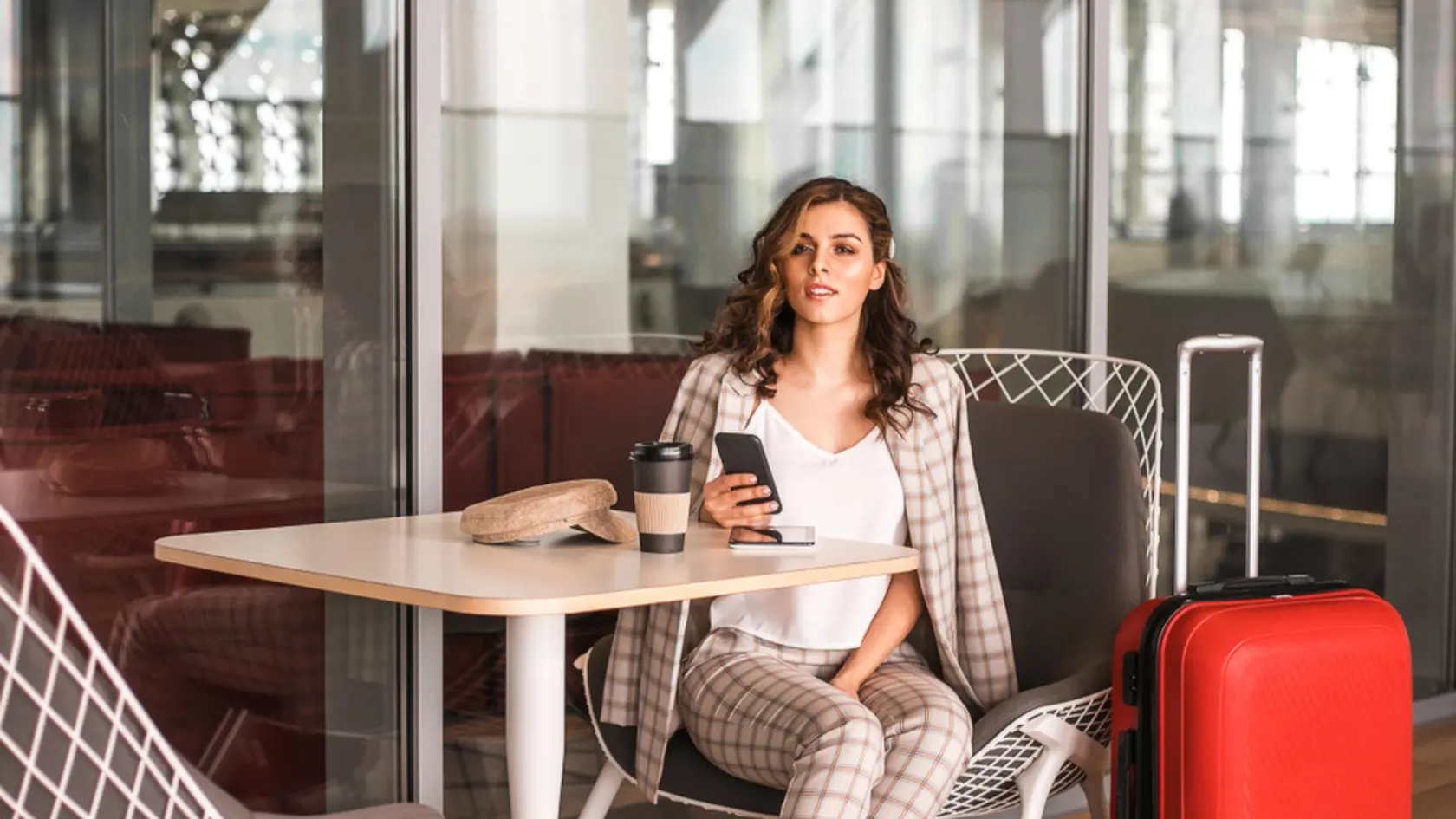 Beautiful business woman with smartphone waiting for her flight in an airport's cafe.