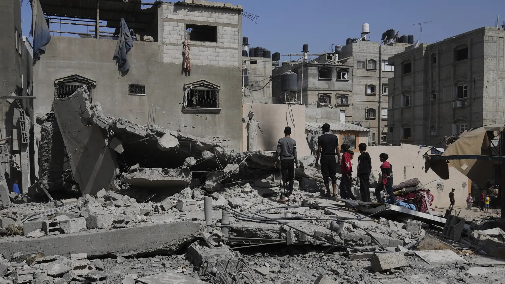 Palestínčania sa pozerajú na zničený dom, ktorý zasiahol útok izraelskej armády v utečeneckom tábore v Chán Júnise v Pásme Gazy v sobotu 3. mája 2025.