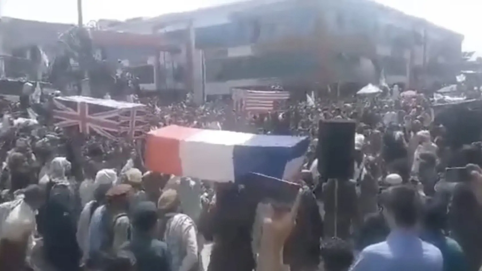 Ľudia v uliciach oslavujú víťazstvo nad USA. Nad hlavami držia rakvy s vlajkami Veľkej Británie, USA a Francúzska.