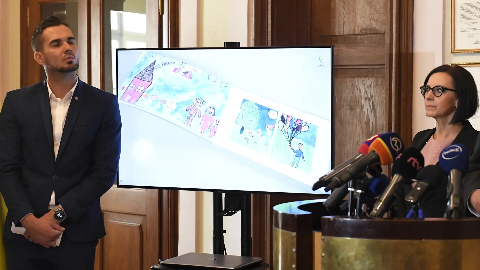 Na na obrazovke kresby detí z Luníka IX, vpravo námestníčka primátora Košíc Lucia Gurbáľová, vľavo hovorca magistrátu Vladimír Fabian počas prezentácie darov pre pápeža Františka 7. septembra 2021 v Košiciach. FOTO TASR – František Iván