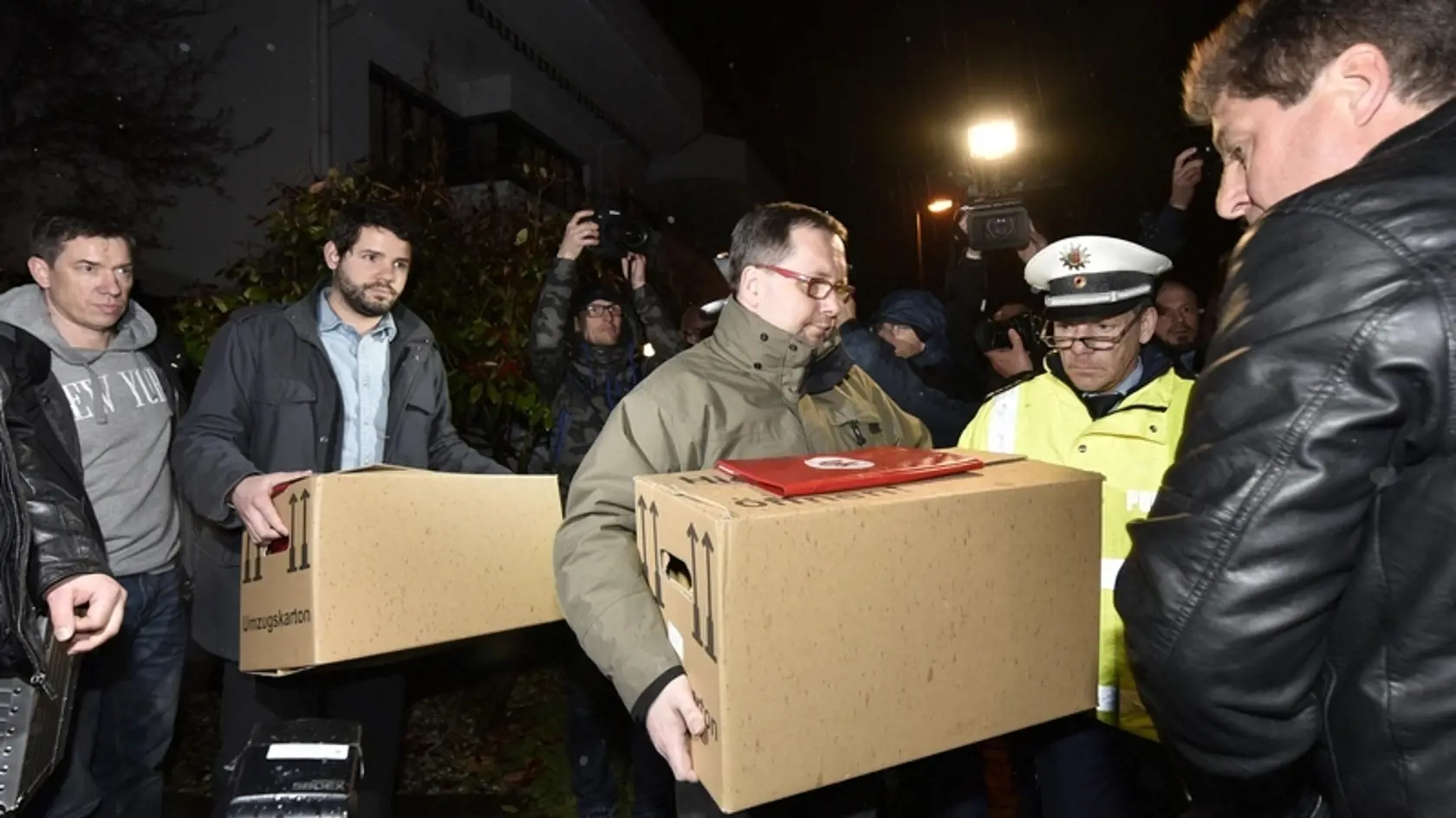 Polícia vynáša z domu kopilota a jeho rodiny plné škatule.