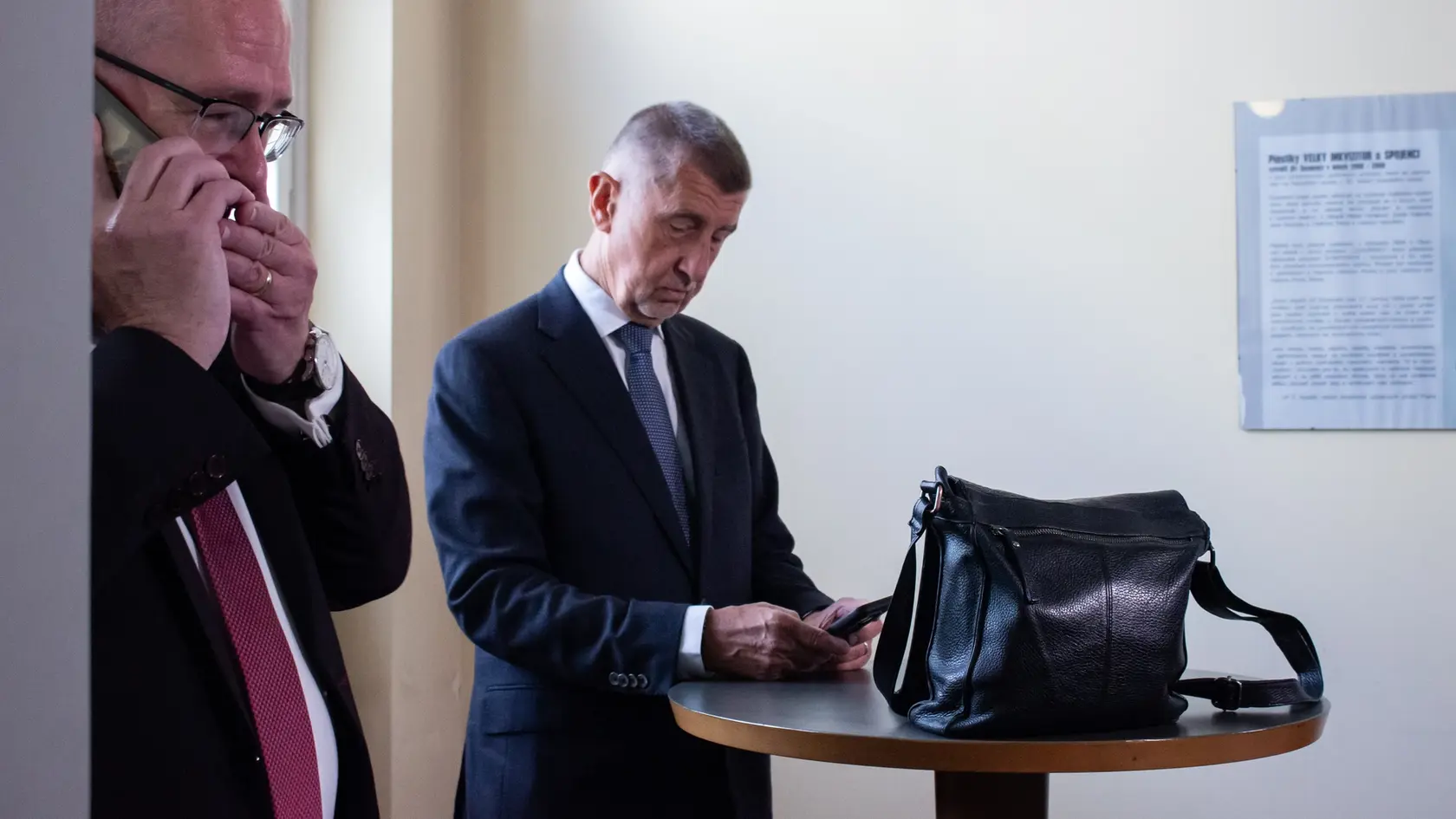 Na snímke český expremiér a predseda hnutia ANO Andrej Babiš (vpravo) si prezerá svoj mobilný telefón pred začiatkom pojednávania v kauze Čapí hnízdo na Vrchnom súde v Prahe. Praha, 26. mája 2025.