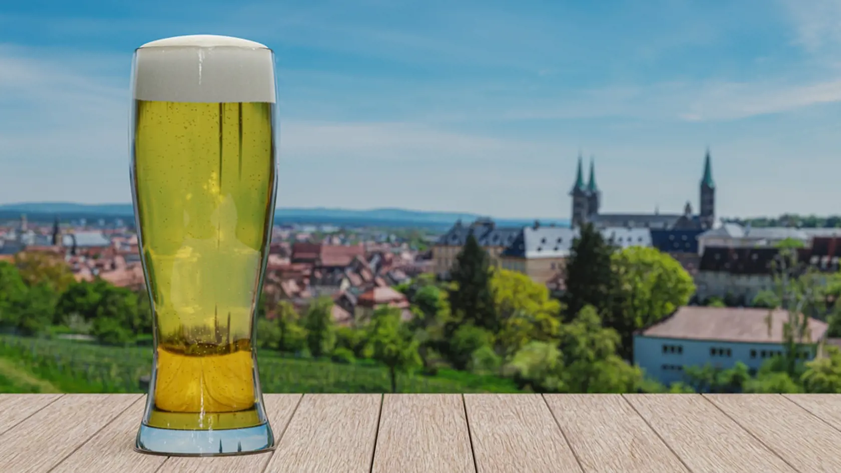 Glass of light beer on panoramic view of fields and historic old town of Bamberg, Germany