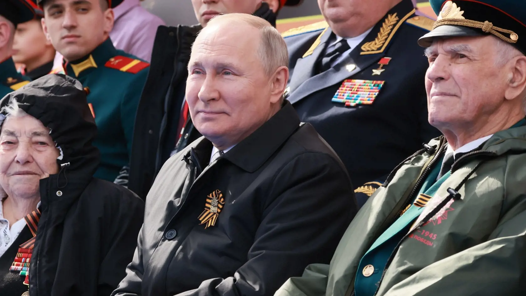 Ruský prezident Vladimir Putin (uprostred) sedí na vojenskej prehliadke pri príležitosti 77. výročia víťazstva nad nacistickým Nemeckom v druhej svetovej vojne na Červenom námestí v Moskve v pondelok 9. mája 2022.