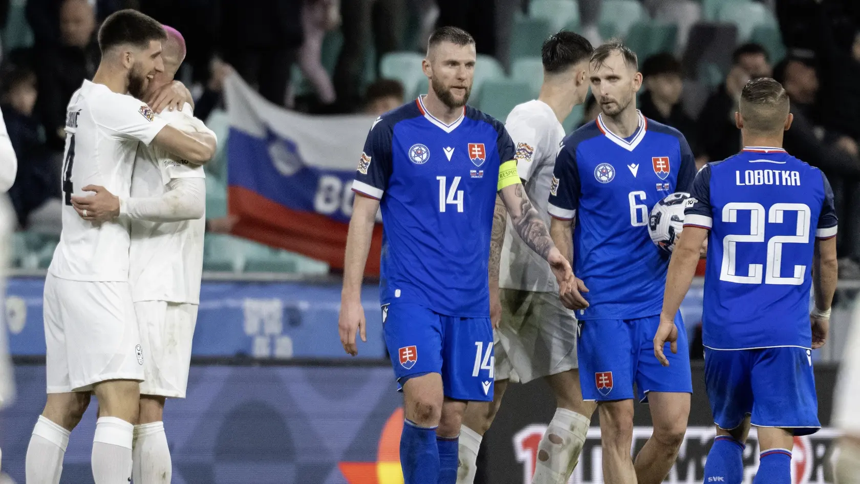 Na snímke sprava sklamaní slovenskí futbalisti Stanislav Lobotka, Norbert Gyömbér, Milan Škriniar a radujúci sa Slovinci po výhre 1:0 v odvetnom zápase play off o postup do B-divízie Ligy národov Slovinsko - Slovensko v Ľubľane.