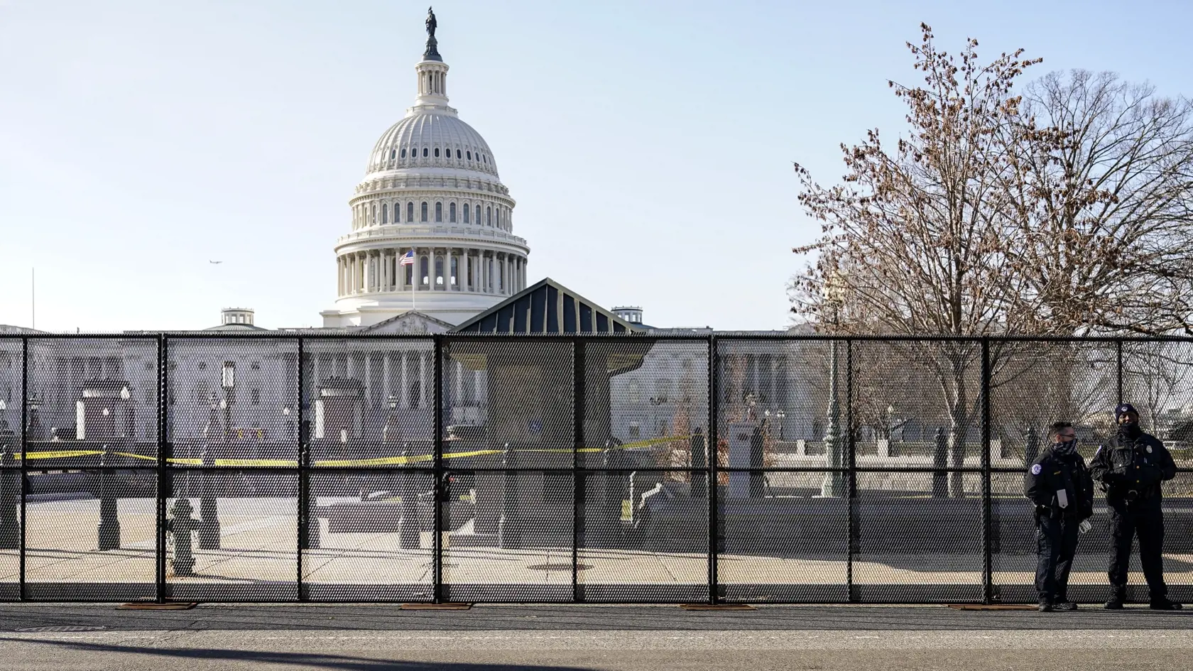 KK2 Washington - Policajti Kapitolu stoja vedľa plota, ktorý inštalovali okolo budovy Kapitolu 7. januára 2021 vo Washingtone.  Okolo budovy Kapitolu, sídla amerického Kongresu vo Washingtone, stavali vo štvrtok dva metre vysoký plot. Opatrenie je reakciou na násilnosti z predchádzajúceho dňa, keď dav ľudí vtrhol do tejto budovy v čase, keď v nej obe komory Kongresu na spoločnom zasadnutí mali potvrdiť víťazstvo Joea Bidena v prezidentských voľbách z 3. novembra. FOTO TASR/AP
Capitol police offi