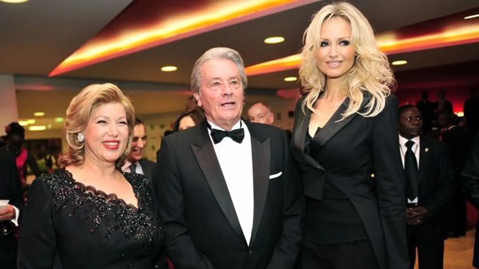 French actor Alain Delon poses with Slovakian model Adriana Karembeu (R) and Ivory Coast first lady Dominique Ouattara upon his arrival for a gala diner of her foundation "Children of Africa" on February 24, 2012 at the Hotel Ivoire in Abidjan. The benefits of the gala will help to build a children/mother Hospital in Bingerville.  AFP PHOTO/ SIA KAMBOU (Photo credit should read SIA KAMBOU/AFP/Getty Images)