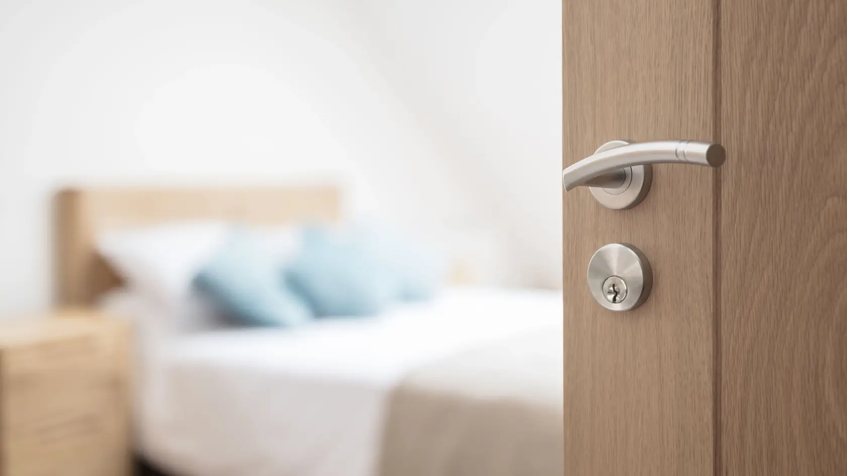 Hotel room or apartment doorway with key and keyring key fob in open door and bedroom in background