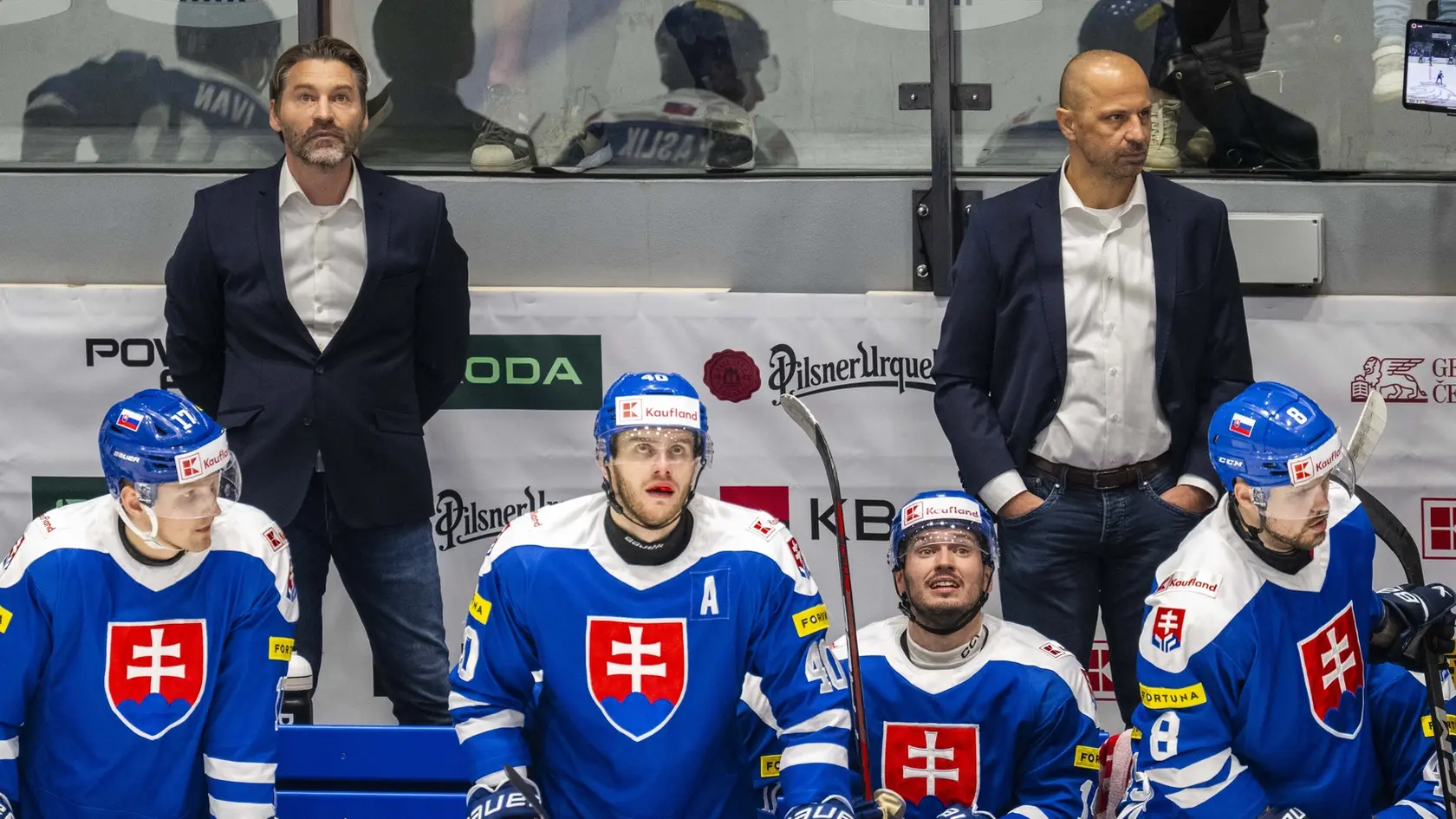 Na snímke hlavný tréner hokejovej reprezentácie SR Vladimír Országh (v pozadá vľavo), jeho asistent Ján Pardavý (v pozadí vpravo), ich zverenci Matej Kašlík (vľavo), Miloš Roman (druhý zľava) a Maxim Čajkovič (vpravo) sledujú zo striedačky.