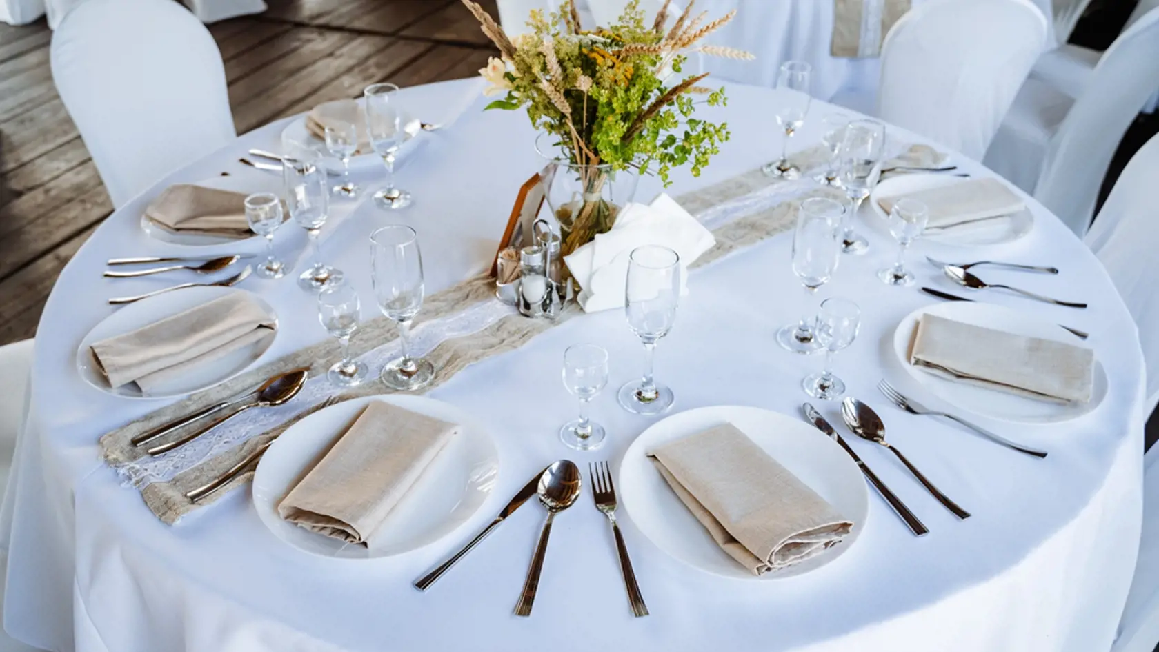 Serving a festive table, placing plates on the table, a Banquet table with a white tablecloth, preparing the dining table for the holiday, Cutlery is arranged according to etiquette. flowers